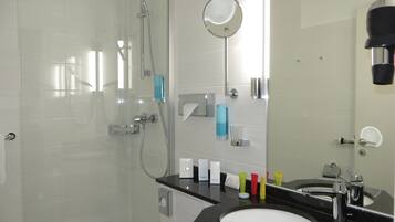 A modern bathroom with a glass shower enclosure, a black countertop sink, and a mirror above the sink.