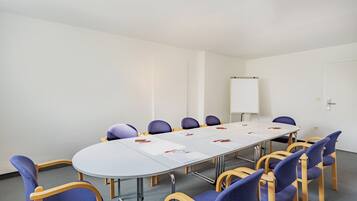 A conference room with a long table, blue upholstered chairs, and a whiteboard.