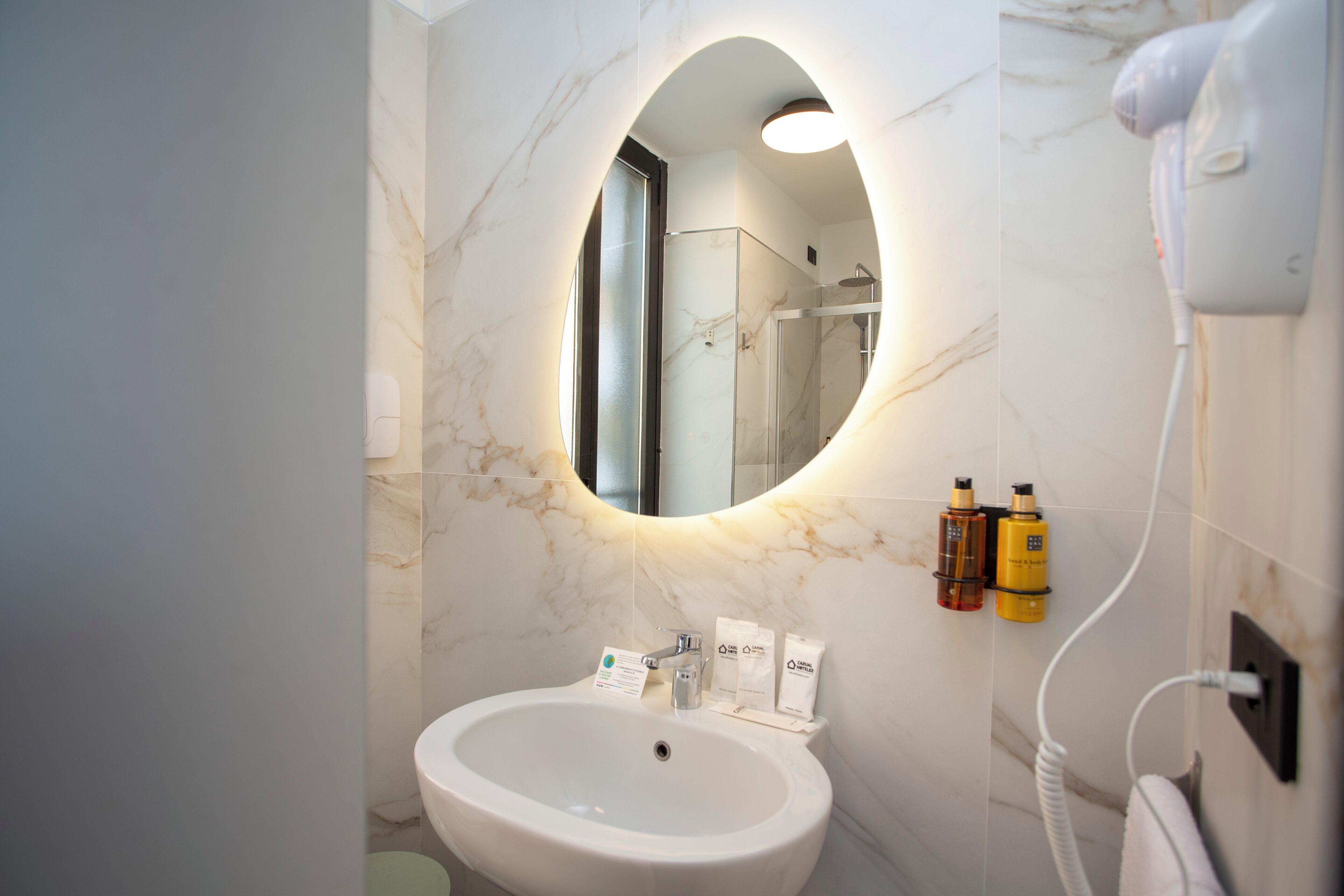 Een badkamer met een marmeren wastafel, een spiegel en toiletartikelen aan de muur.