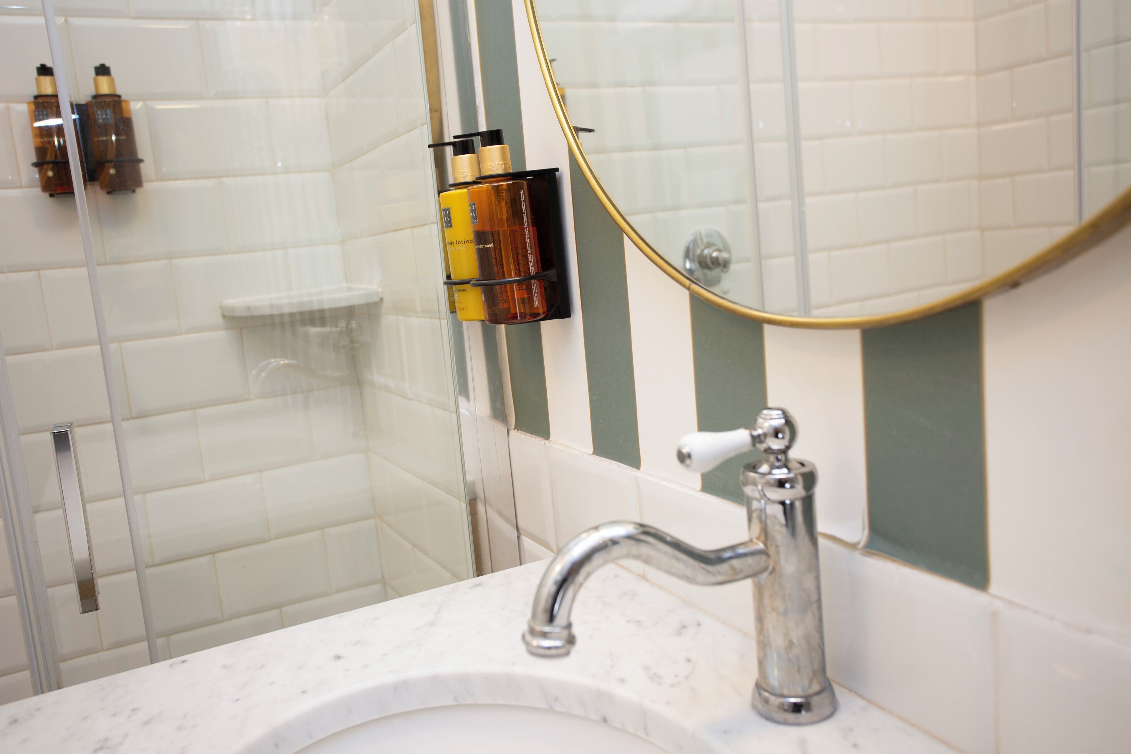 Un bagno con un lavandino bianco, un rubinetto cromato e uno spazio doccia in vetro.
