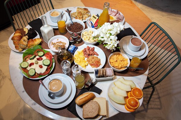 Une table de petit-déjeuner avec divers plats, notamment des œufs, des toasts, des fruits et des boissons.
