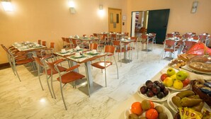 Un comedor con mesas y sillas, una exhibición de frutas y una puerta al fondo.