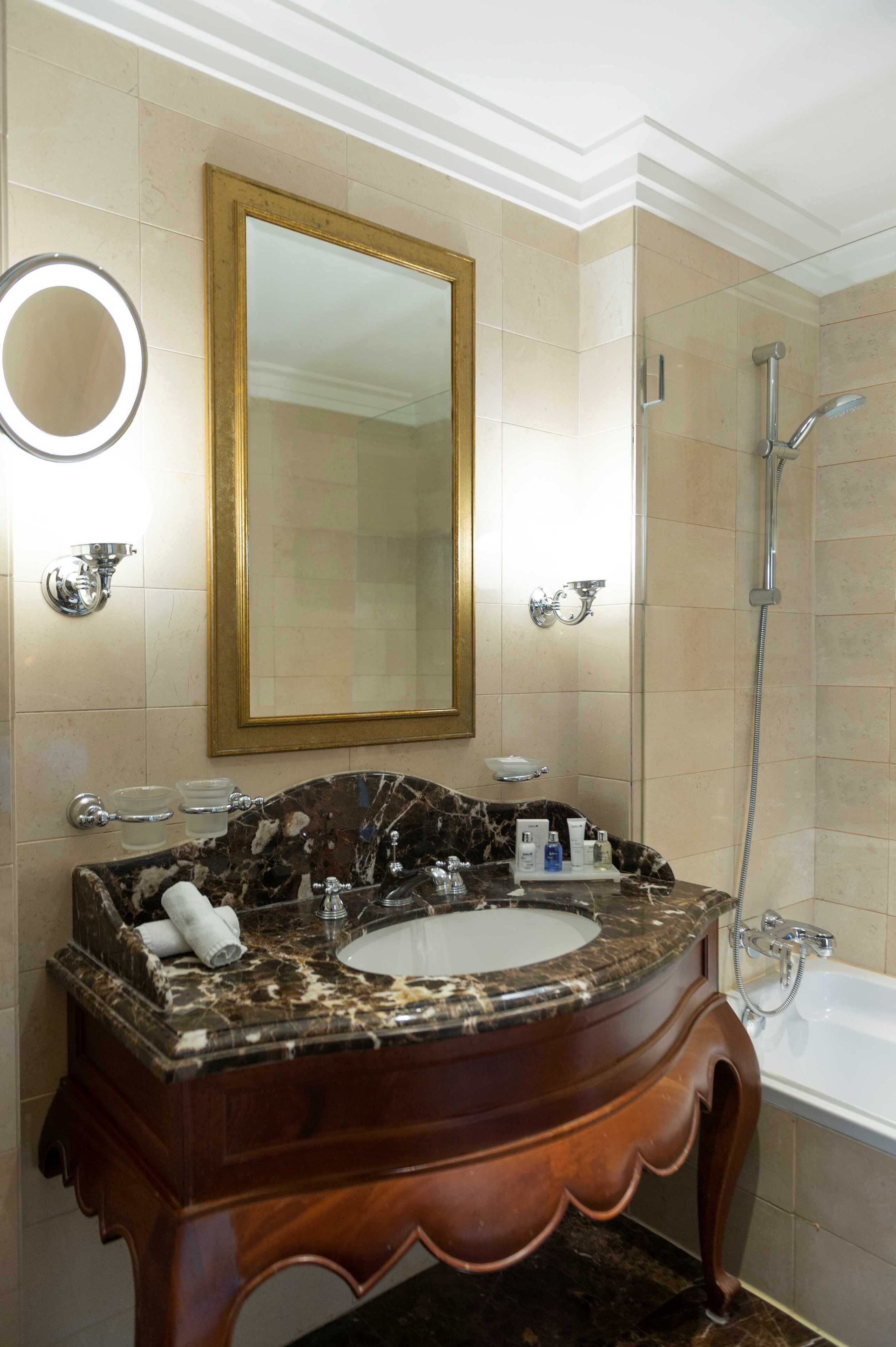 A bathroom with a marble sink, a large mirror, a shower, and a bathtub.