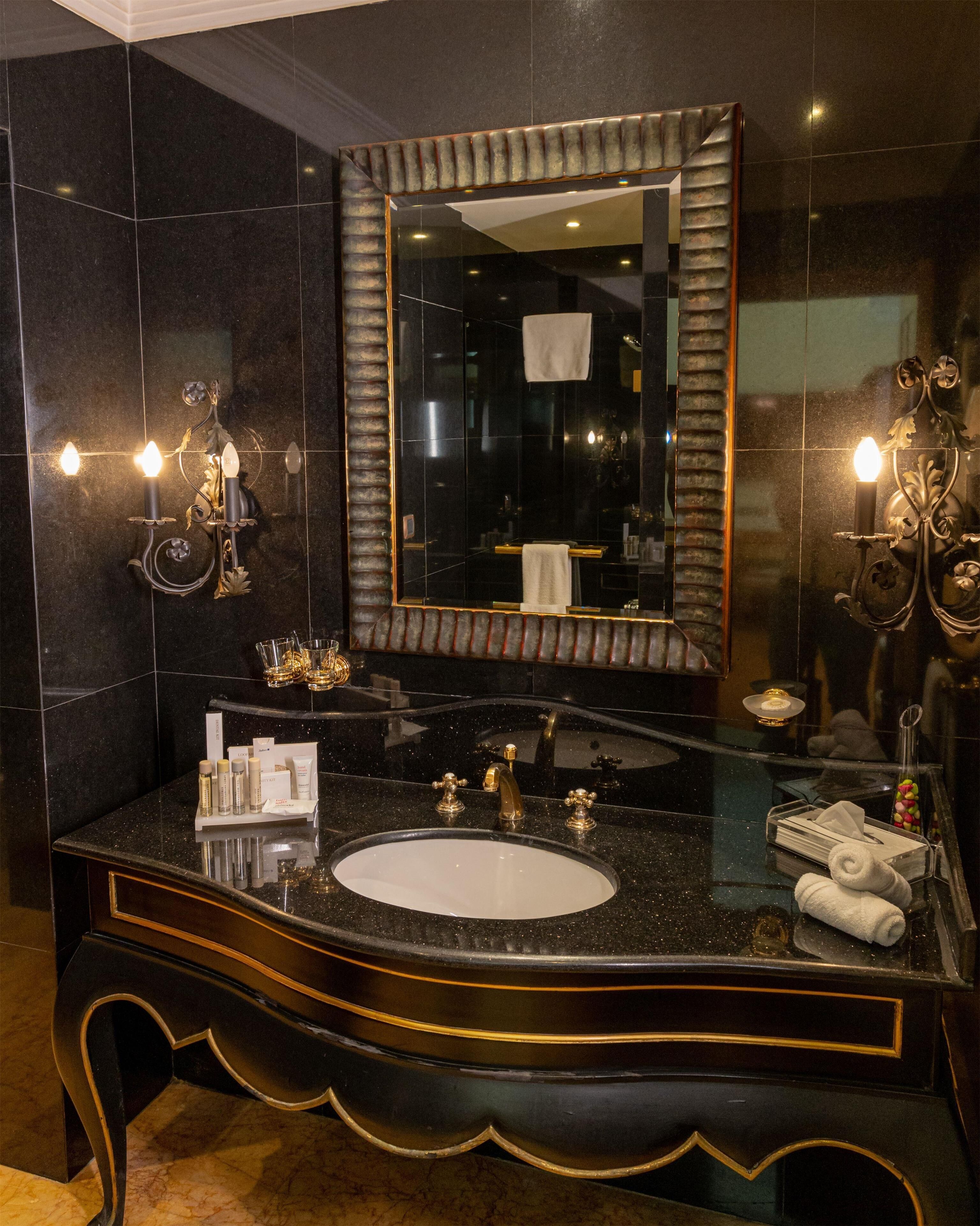 A bathroom with a large mirror, a sink, and wall sconces.