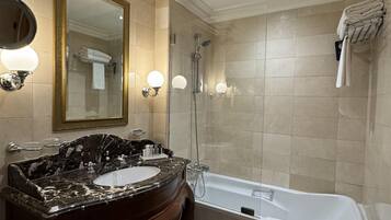 A bathroom with a marble vanity, a large mirror, a bathtub, and a glass-enclosed shower.