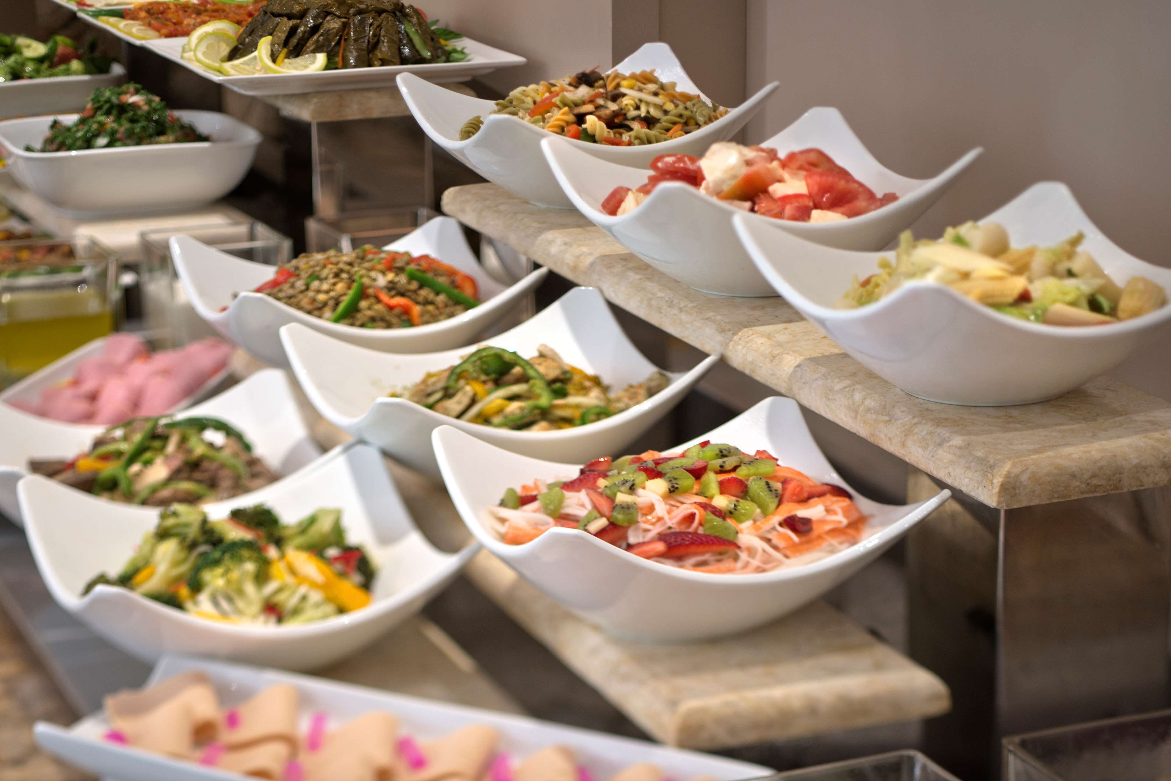 A buffet with various dishes in white bowls.