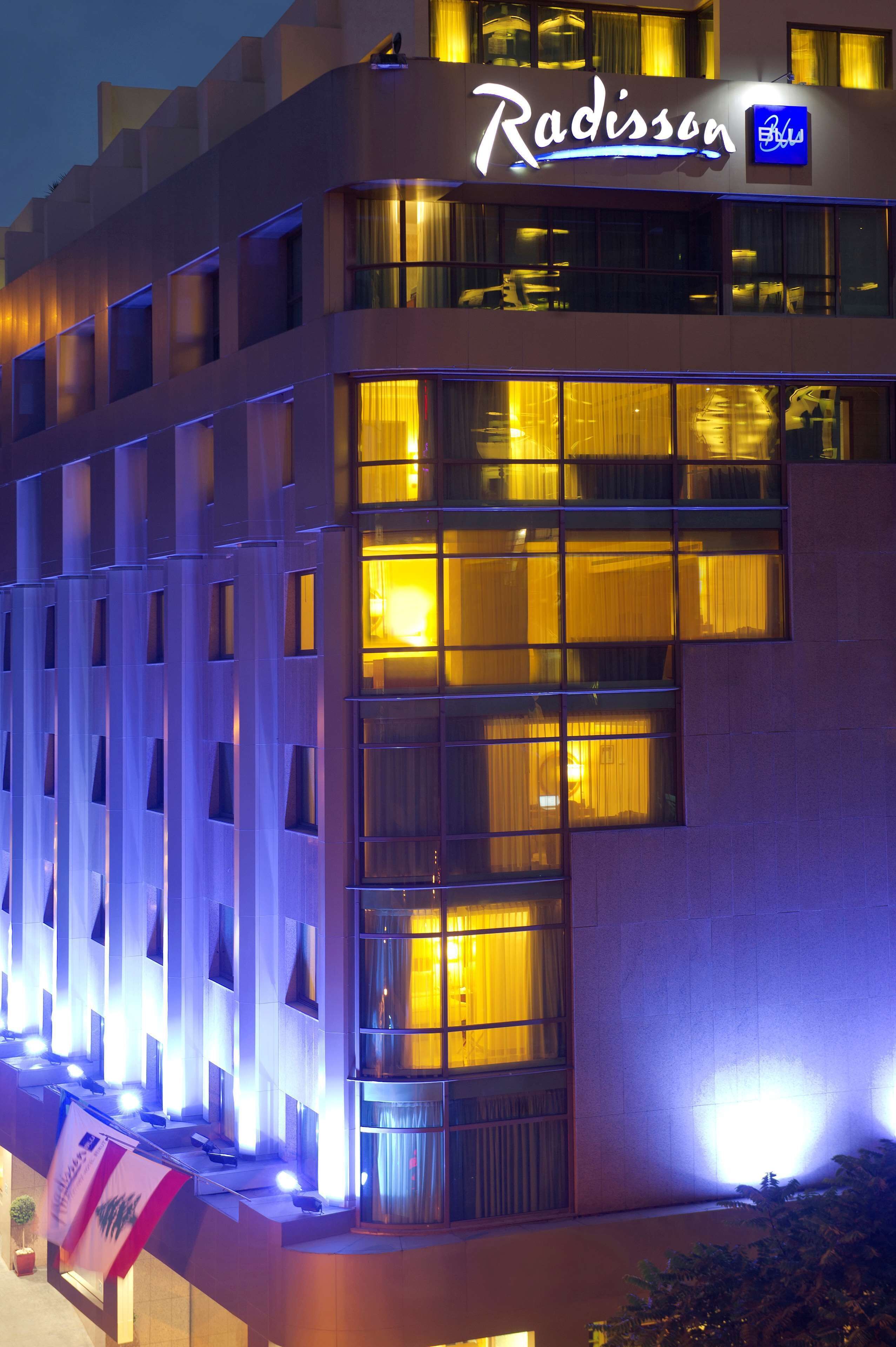 Un hotel con fachada moderna, señalización iluminada y varias ventanas.
