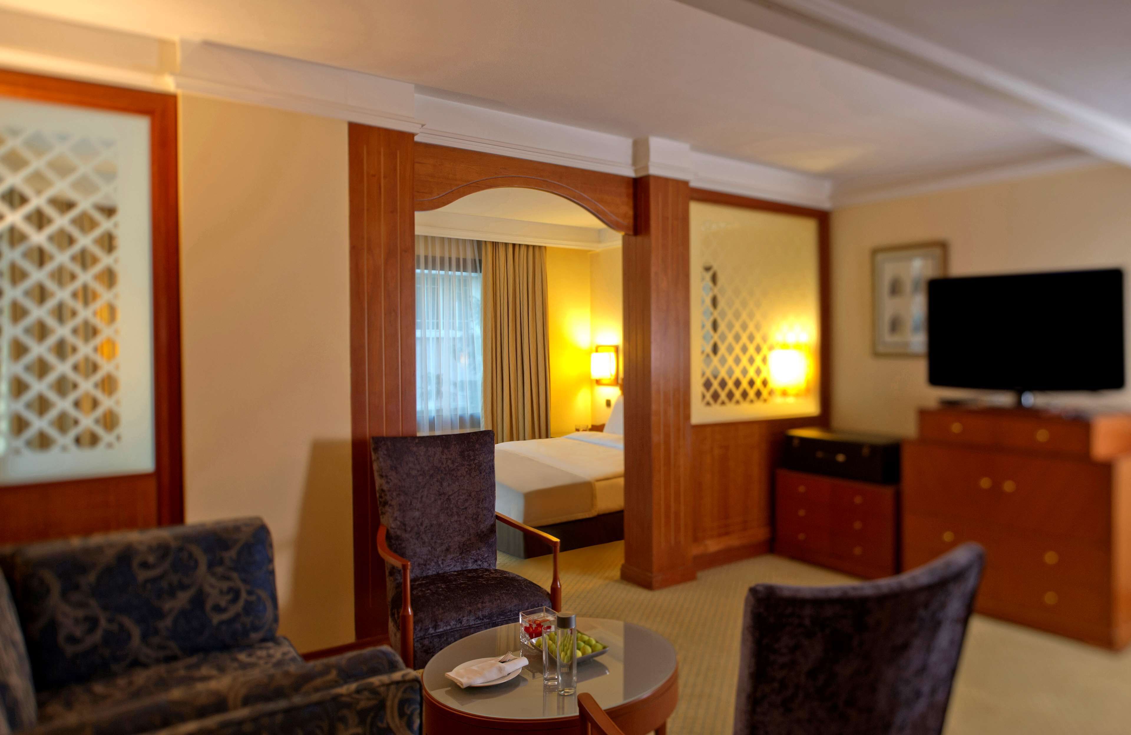 A hotel room with a bed, a TV, a desk with a chair, and a sofa.