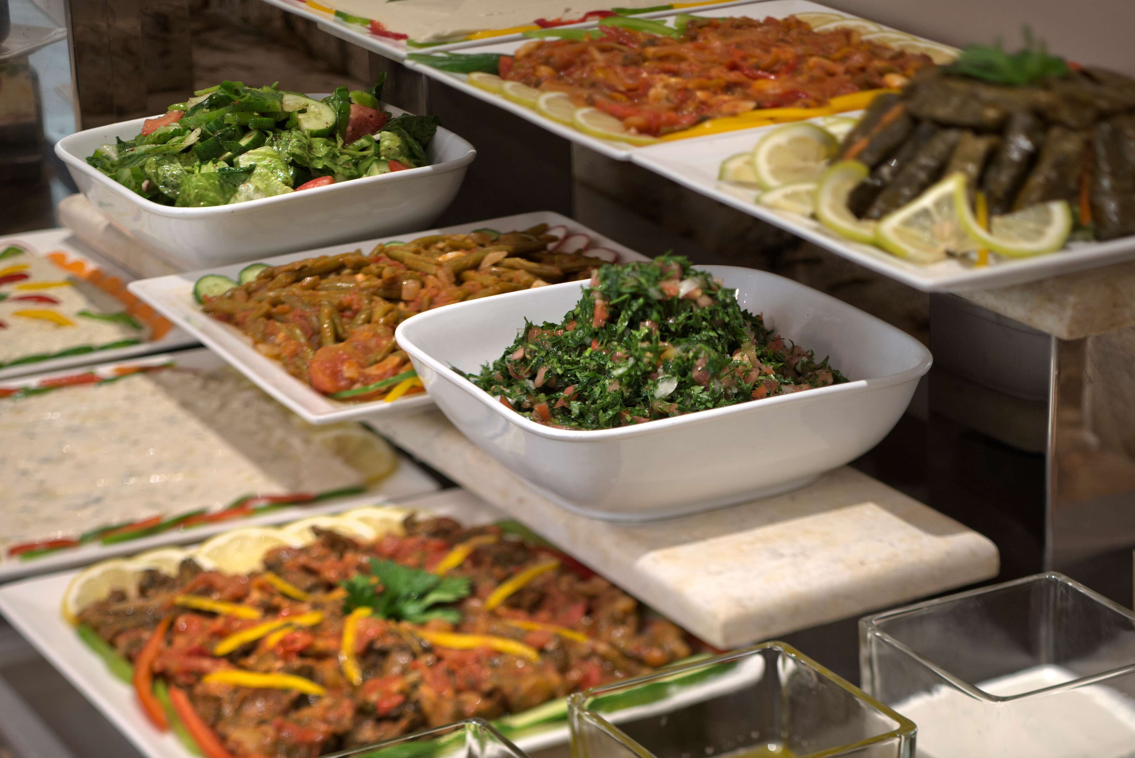 A buffet with various dishes including salads, pasta, and meat dishes.