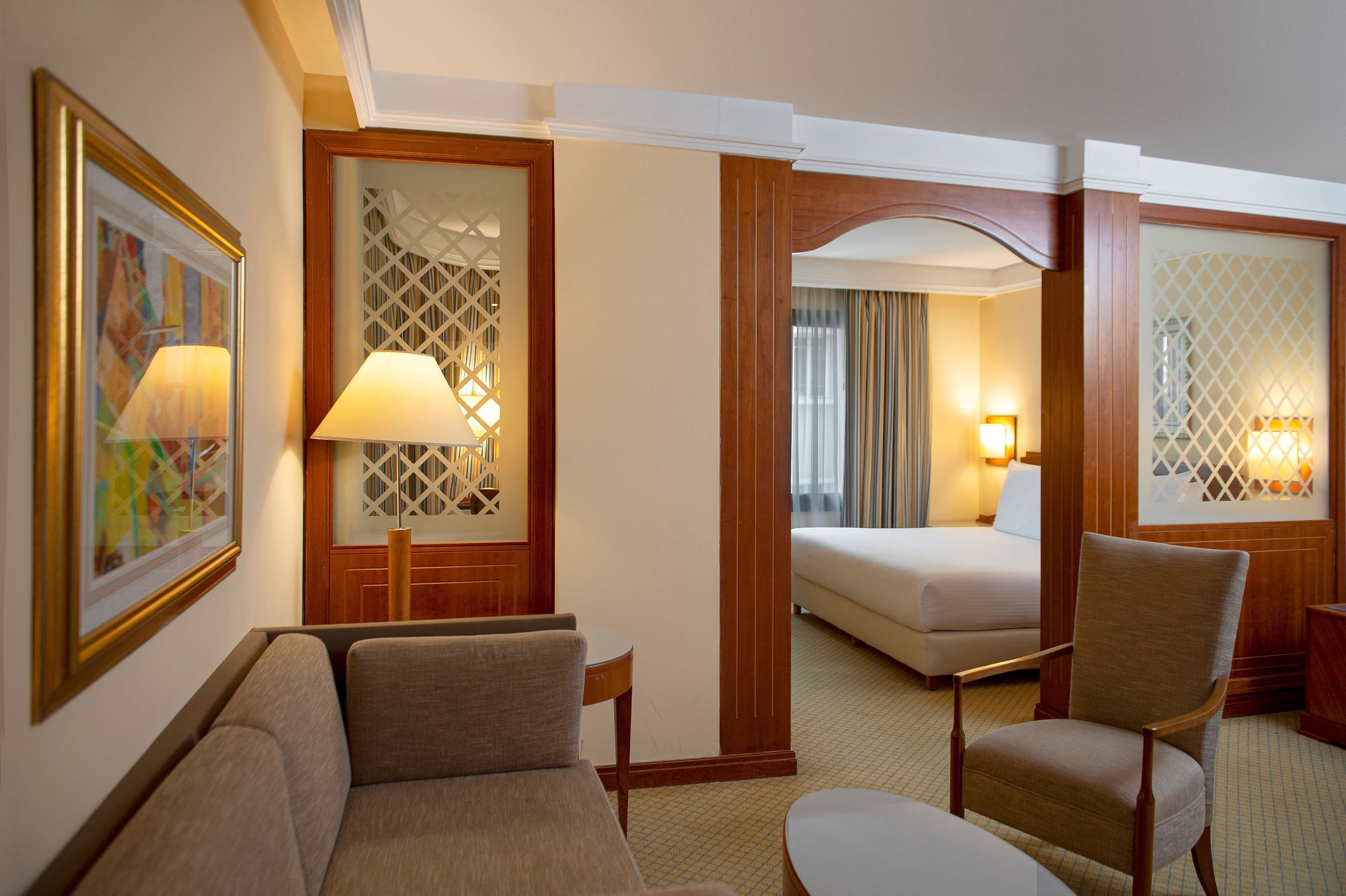 A hotel room with a sofa, armchair, and a bed.