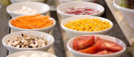 Un bufé con diversos alimentos, entre ellos verduras, frutas y quesos.