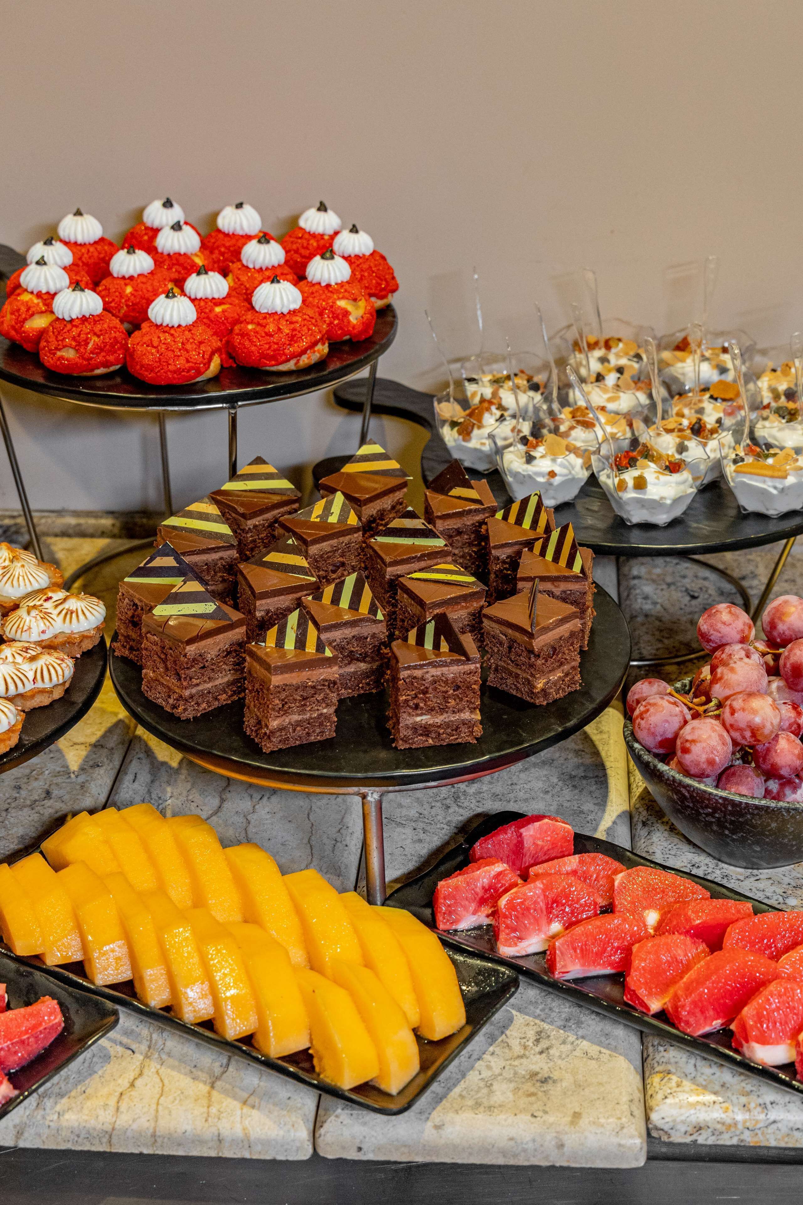 Un bufé con diversos postres y frutas.