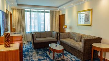 A hotel room with two sofas, a small table, a lamp, and a framed picture on the wall.