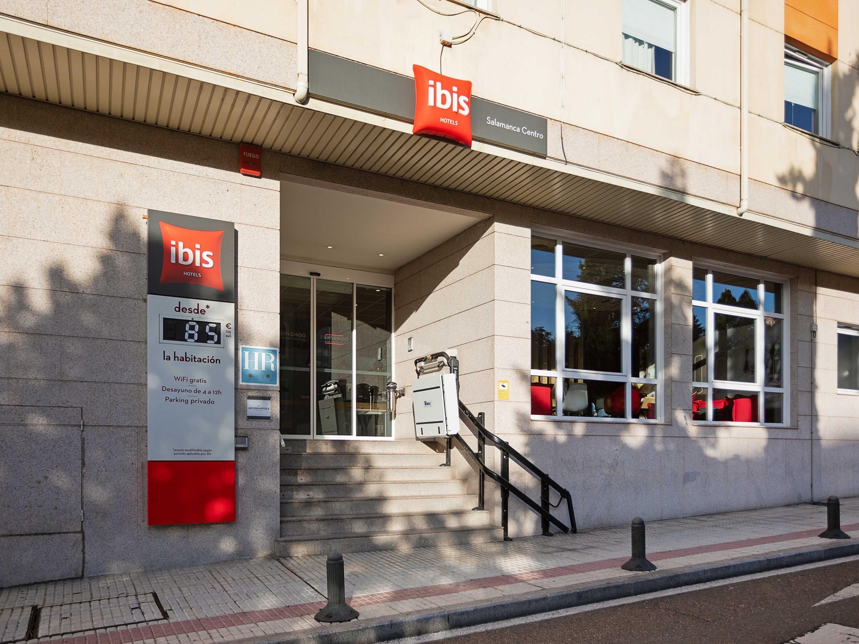 Ein Hotel Eingang mit einer Treppe, die zum Eingang führt, einer Beschilderung mit 'ibis Hotels' und 'Salamanca Centro' sowie einer digitalen Anzeige mit dem Preis '89€'.