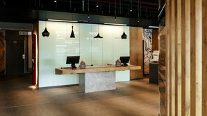 Een receptiebalie met een digitaal scherm, een houten toonbank en een moderne lamp.
