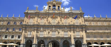 Un edificio histórico con arquitectura ornamentada, varios arcos y banderas.