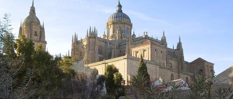 A large historic building with multiple domes and spires, surrounded by well-maintained gardens.