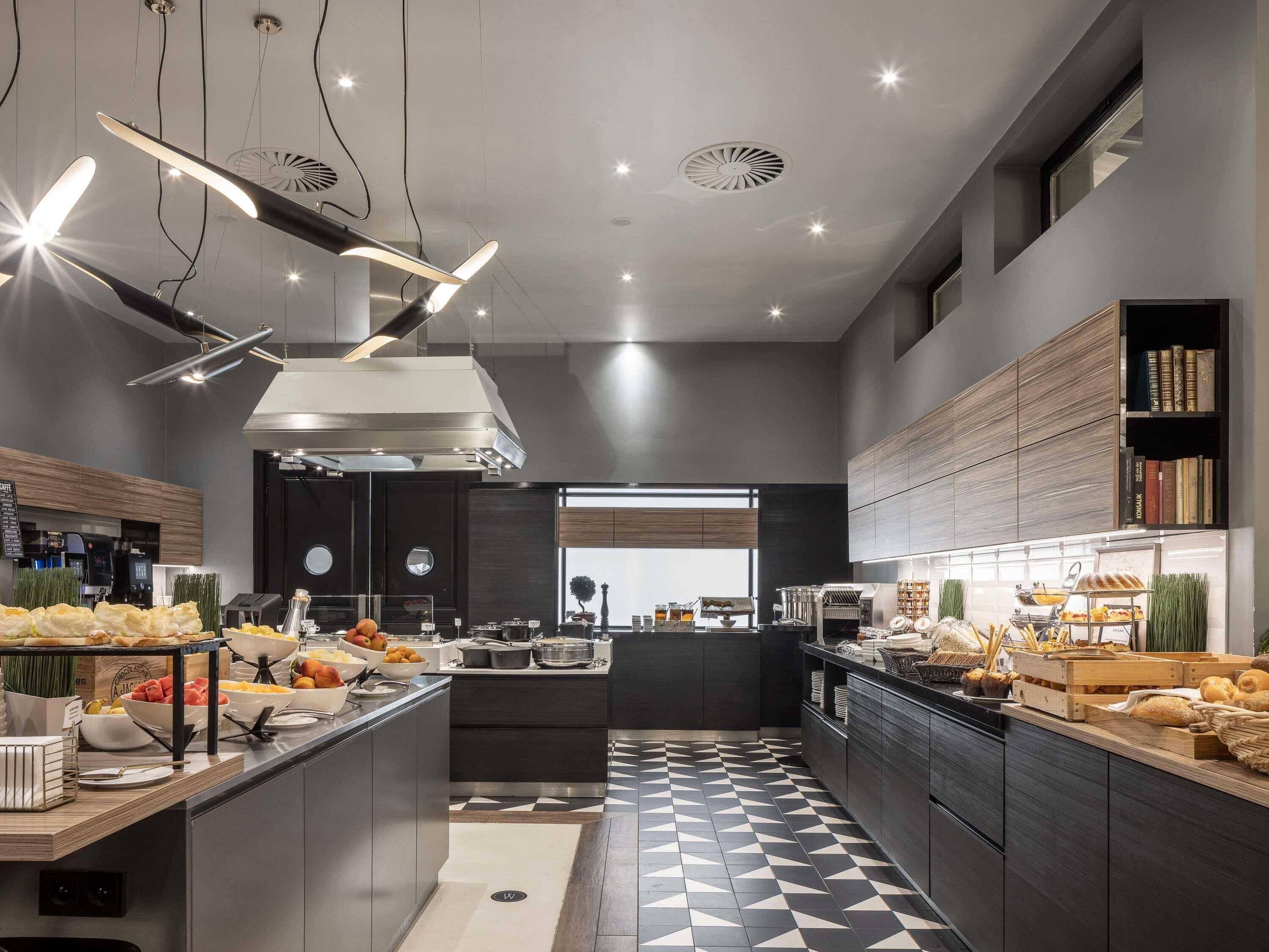 A modern kitchen with a central island, built-in appliances, and a variety of food items displayed.