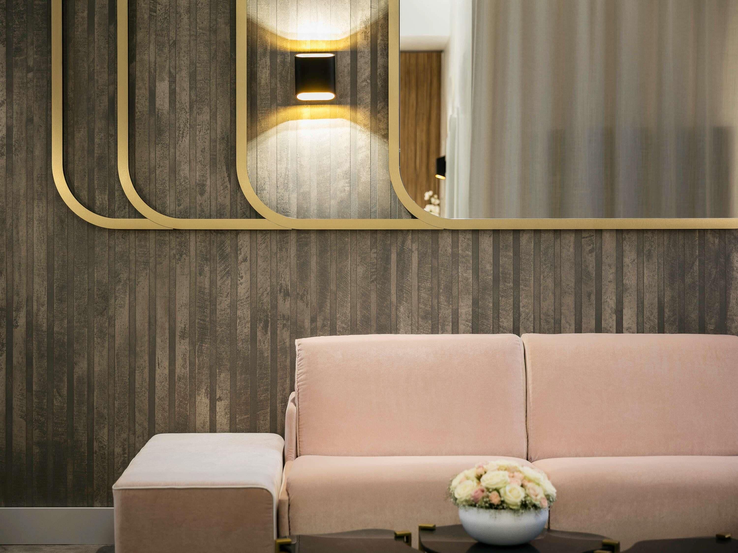 Een kamer met een bank, een poef en een tafel met een bloemetjesvaas.