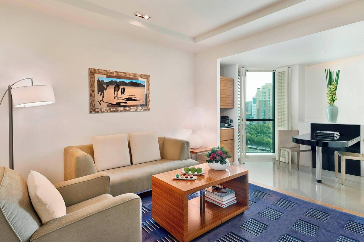 A modern living room with a sofa, coffee table, and a painting on the wall.