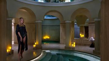 Relax by the central pool surrounded by arches and columns in a serene, high-end setting.