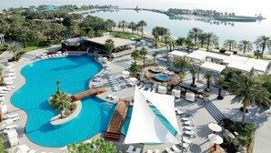A resort with a large pool, sun loungers, a hot tub, and a view of the sea.