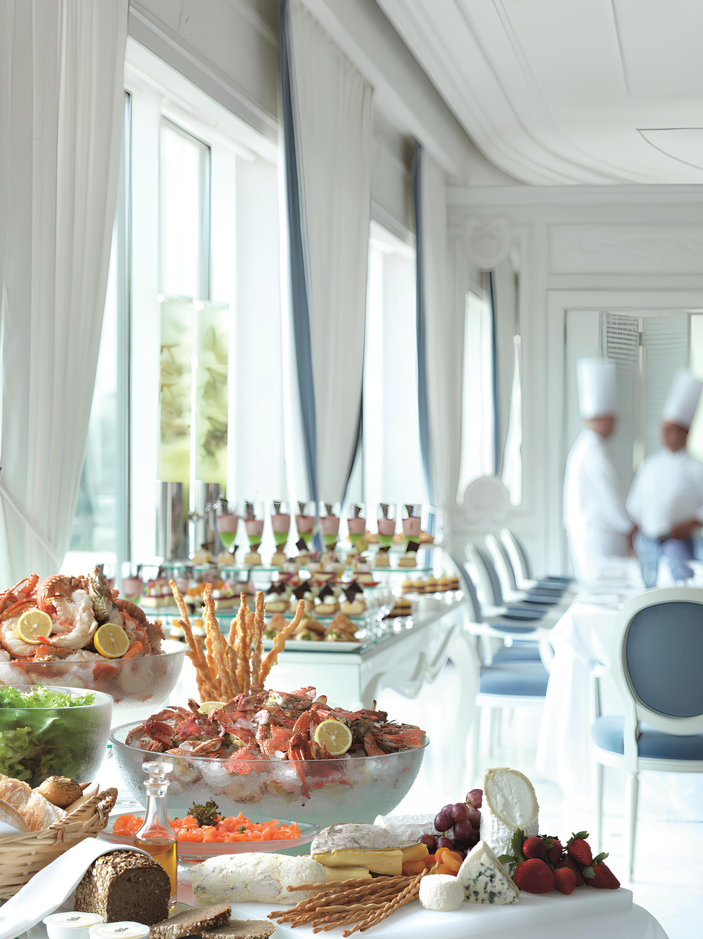 A buffet table with seafood, cheeses, and fruits.