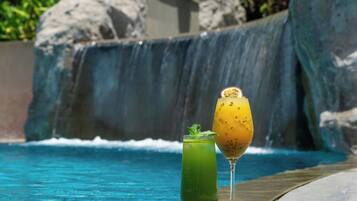 A poolside area with a clear view of the ocean, a waterfall, and lush greenery.