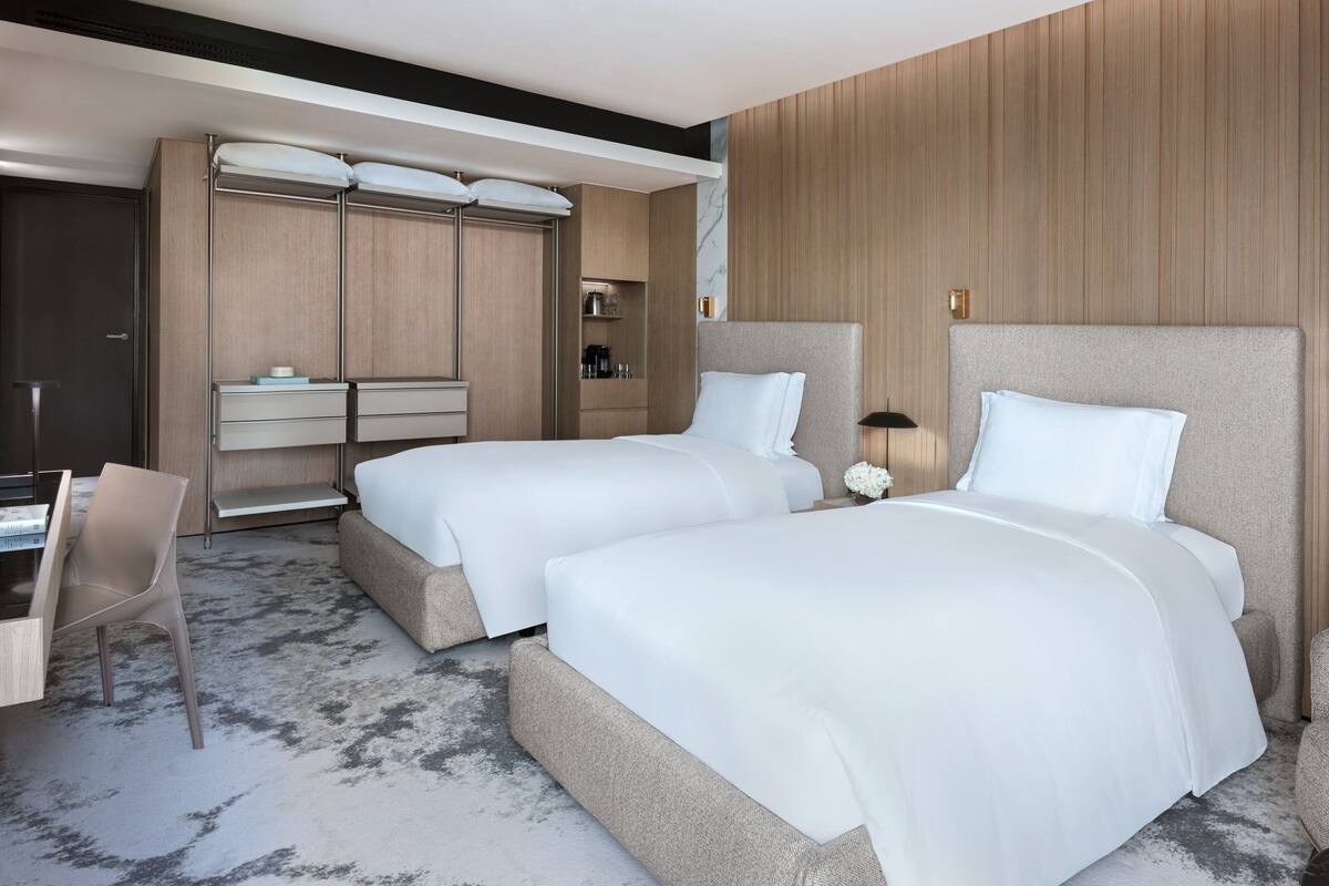 A hotel room with two beds, a desk, and a wardrobe.