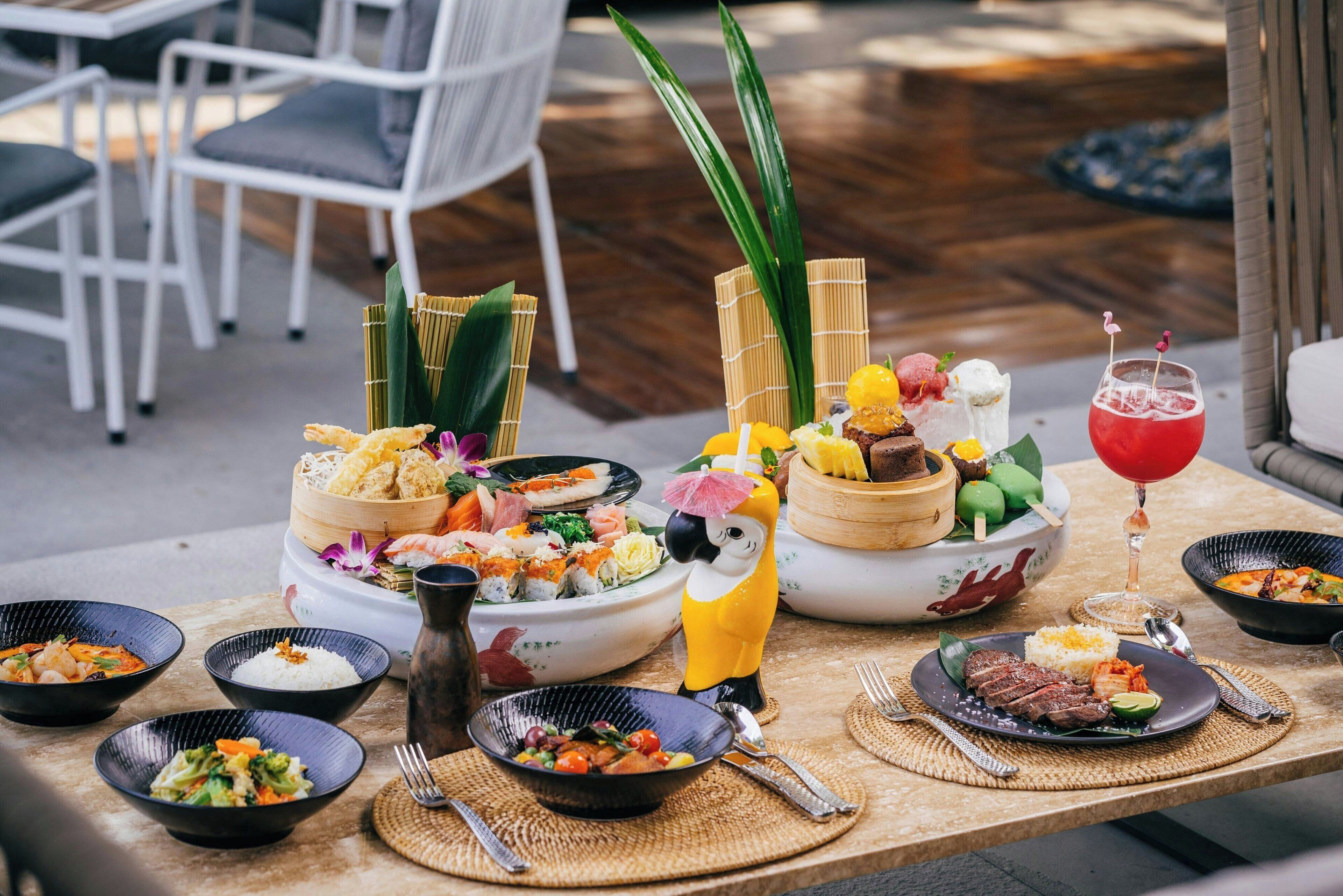 Una mesa dispuesta con varios platos, incluyendo sushi, arroz y carne, junto con una bebida.