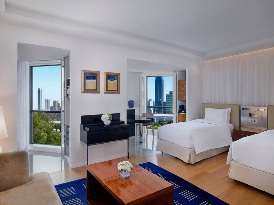 Habitación de hotel moderna con una cama grande, un escritorio y vistas a la ciudad.