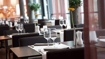 A restaurant with tables set for dining, featuring clear glassware and a vase with a single flower.