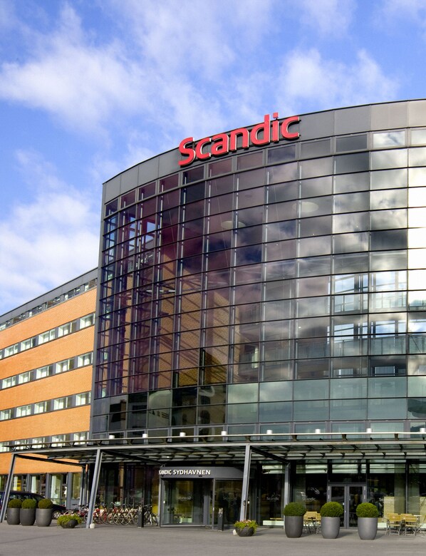 Un bâtiment moderne avec une façade en verre et le nom « Scandic » affiché en évidence.