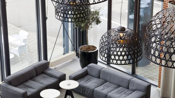 A modern lounge area with grey sofas, red chairs, and round tables. - Scandic Sydhavnen (Copenhagen)