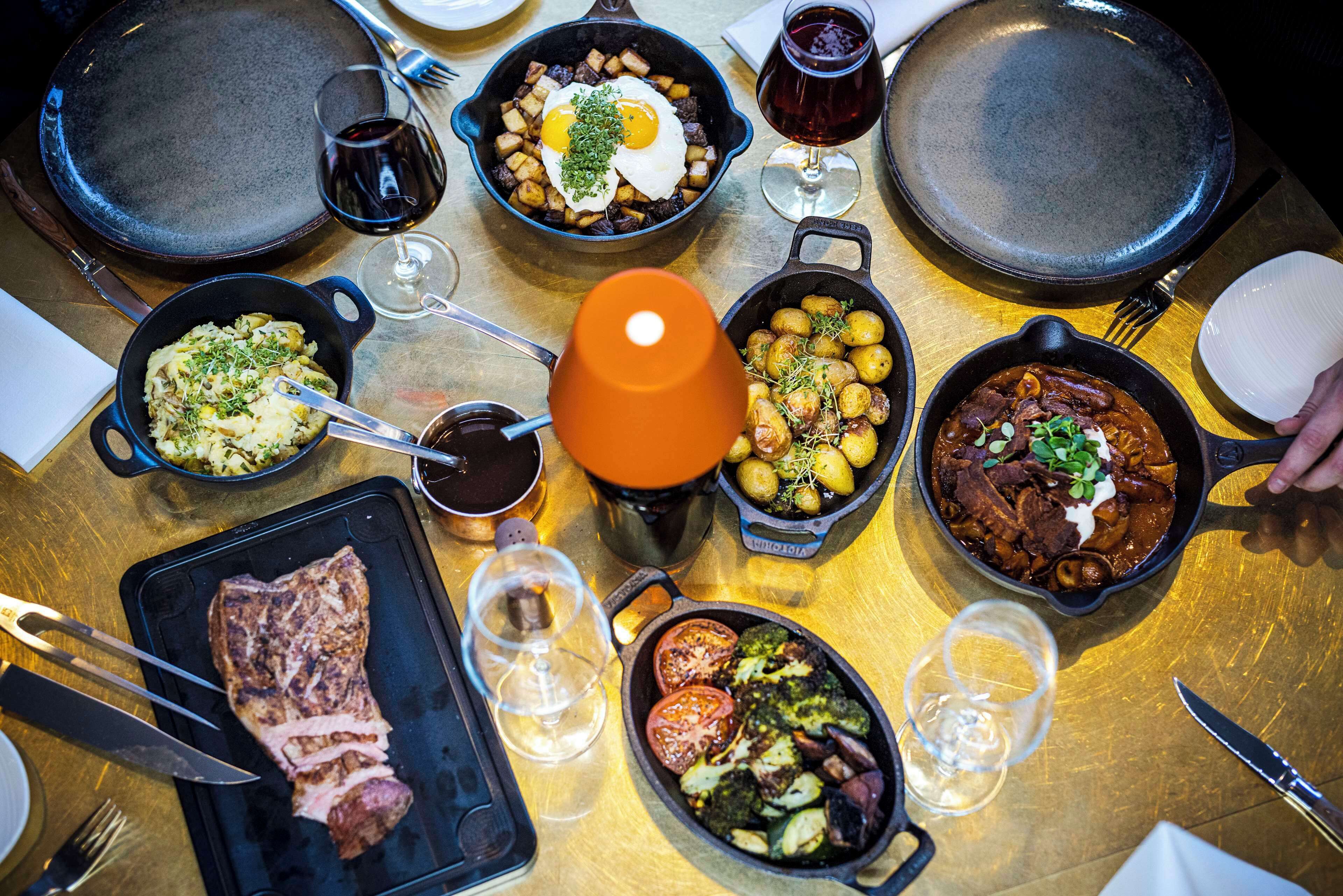 A table with various dishes, including eggs, potatoes, and meat, along with wine glasses and cutlery.