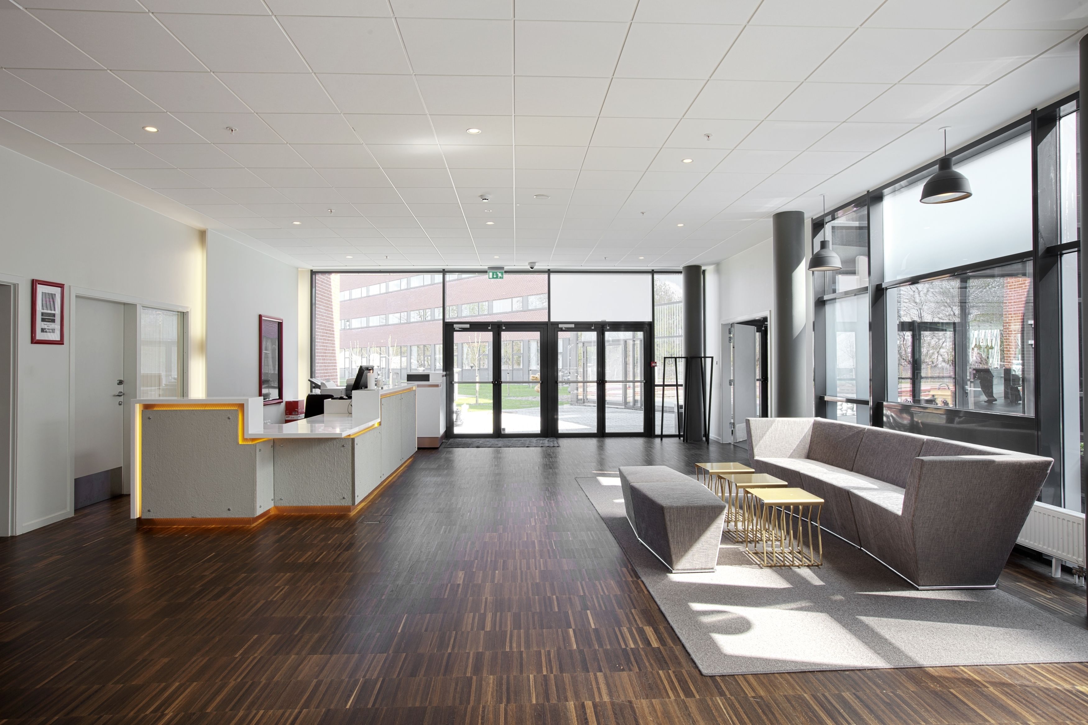 A spacious lobby with a reception desk, a grey sofa, and a coffee table.