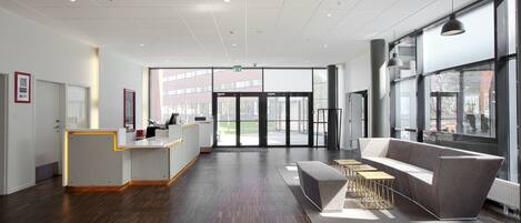 A spacious lobby with a reception desk, a grey sofa, and a coffee table.