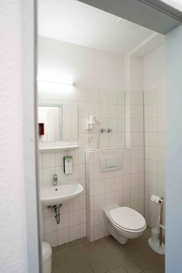 A small, clean bathroom with a white sink, toilet, and mirror.