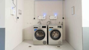 A small laundry room with two washing machines and a wall-mounted dryer. - Plaza Inn Hannover City Nord (Hannover)