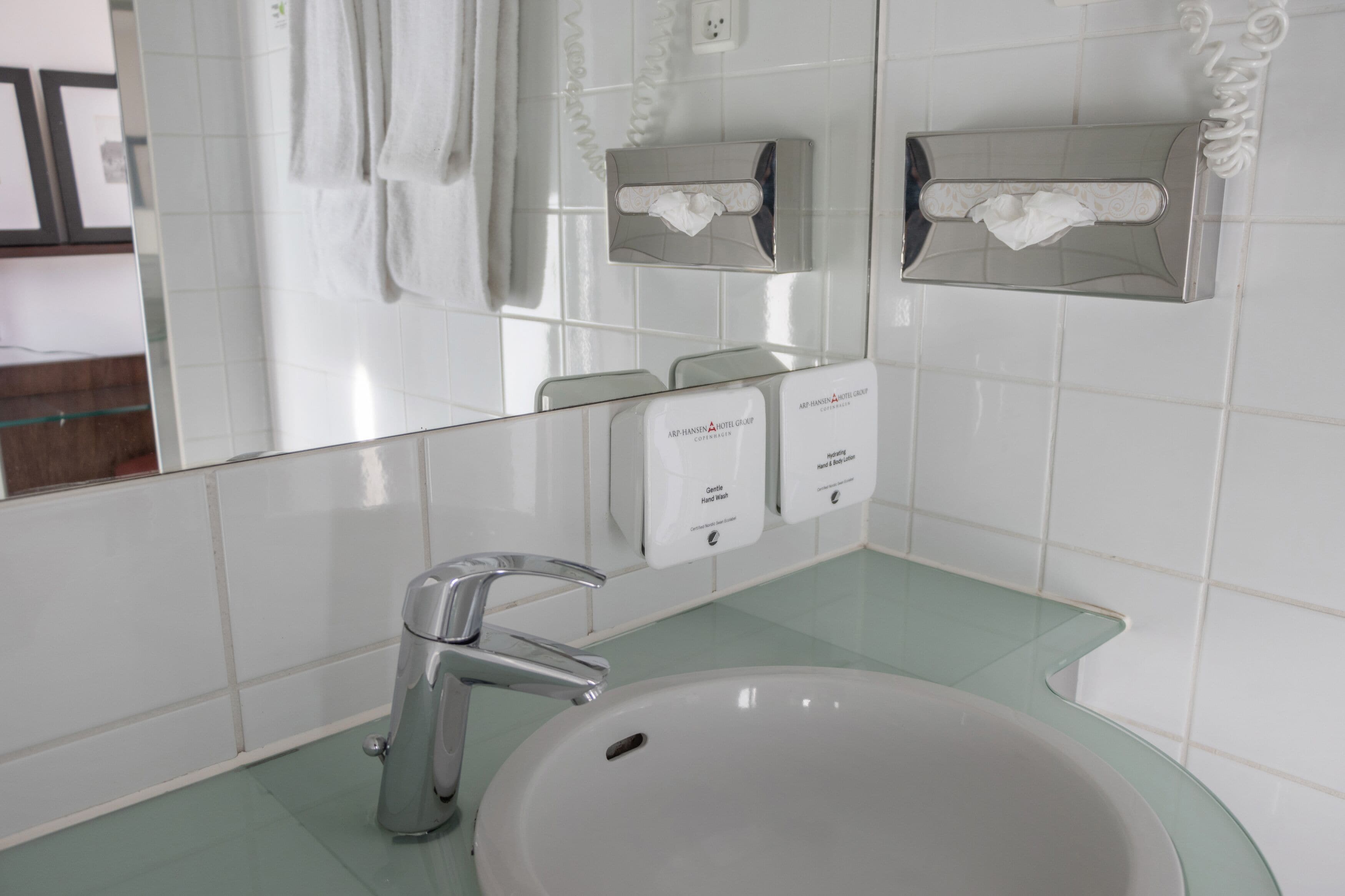 A bathroom with a white sink, a mirror, and two hand sanitizer dispensers.