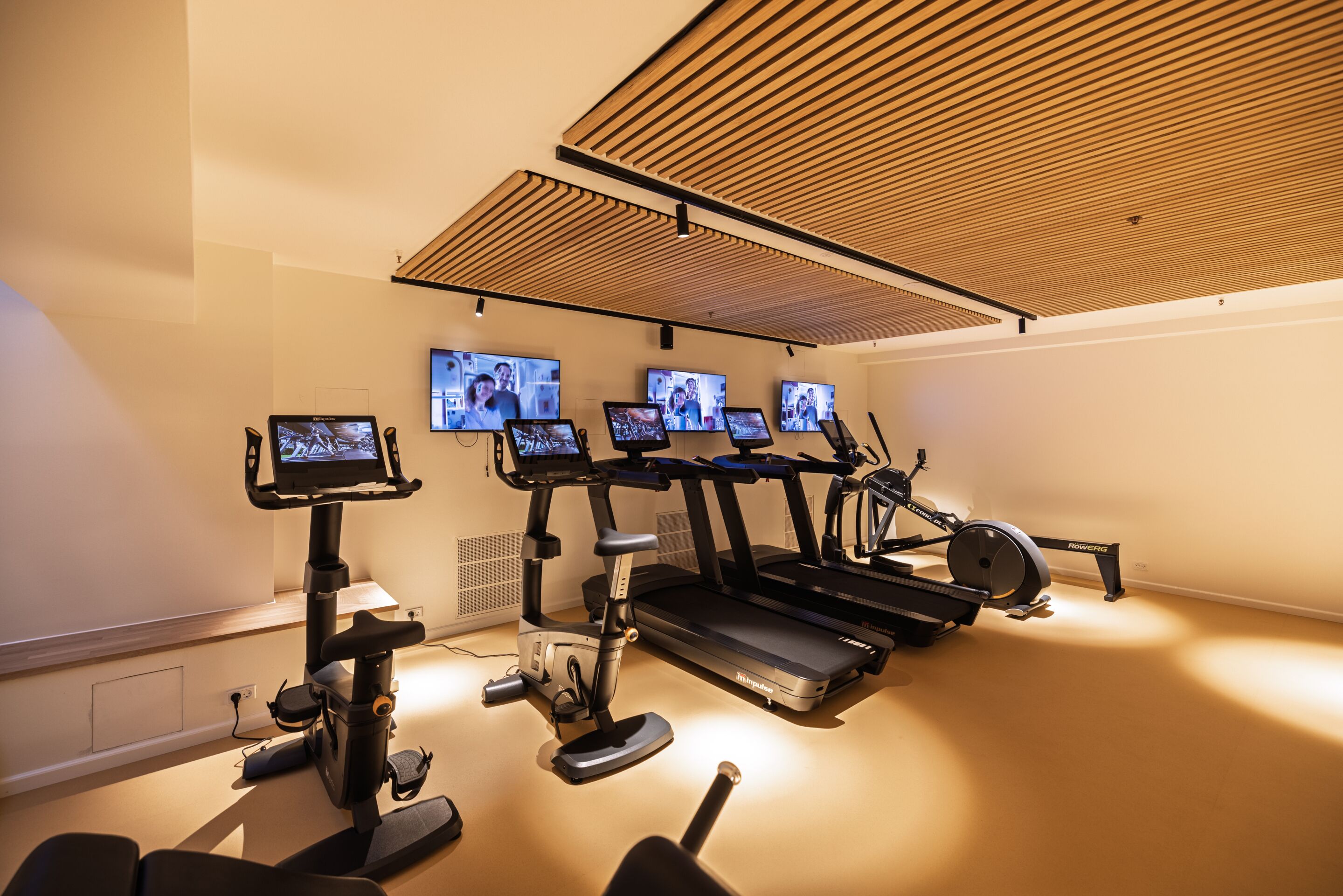 Un gimnasio con cintas de correr, bicicletas estáticas y equipamiento de ejercicio.