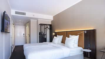 Una habitación de hotel moderna con una cama grande, una mesita de noche, un televisor en la pared y un vestidor.
