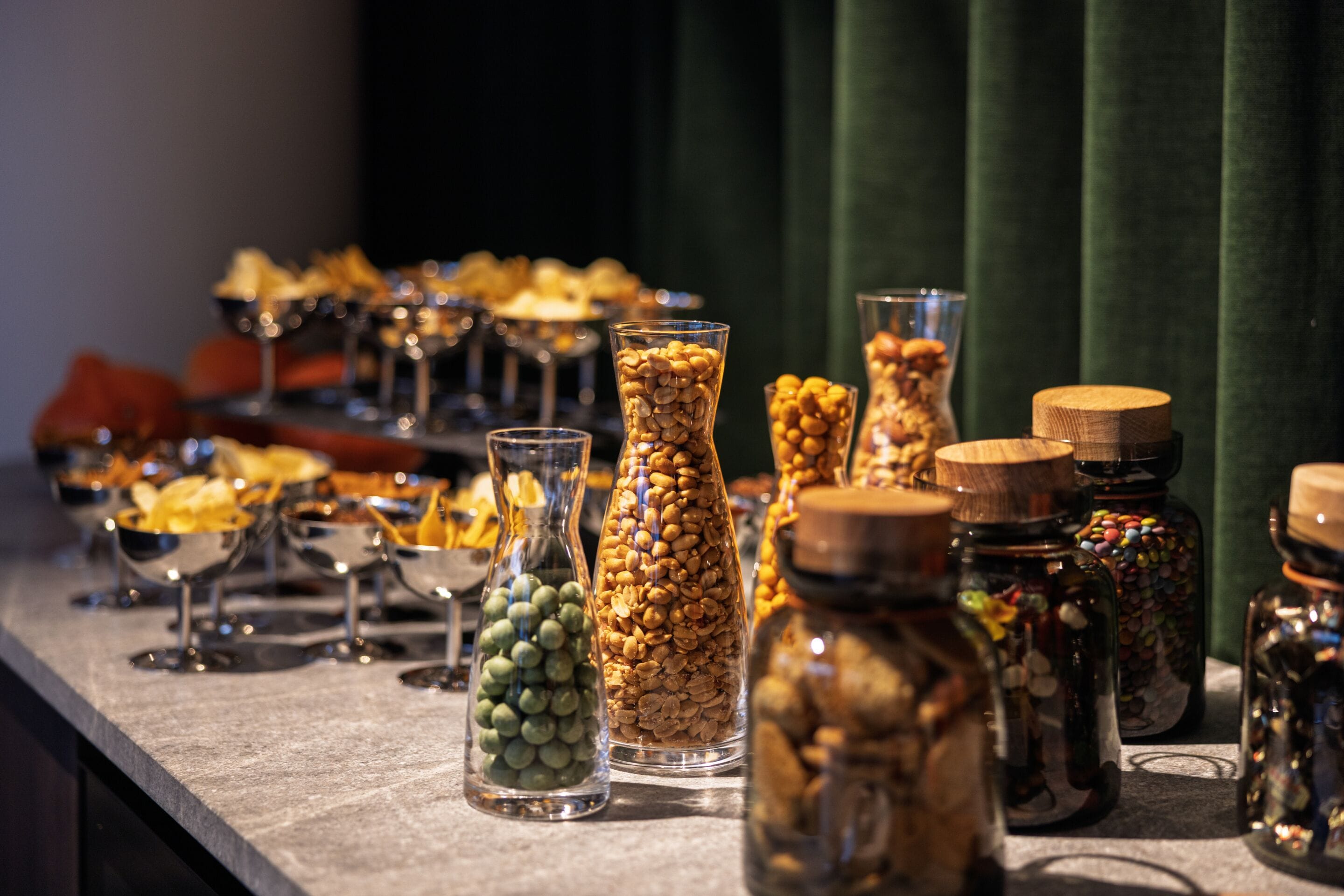 Een buffet met diverse gerechten, potten noten en snoep.