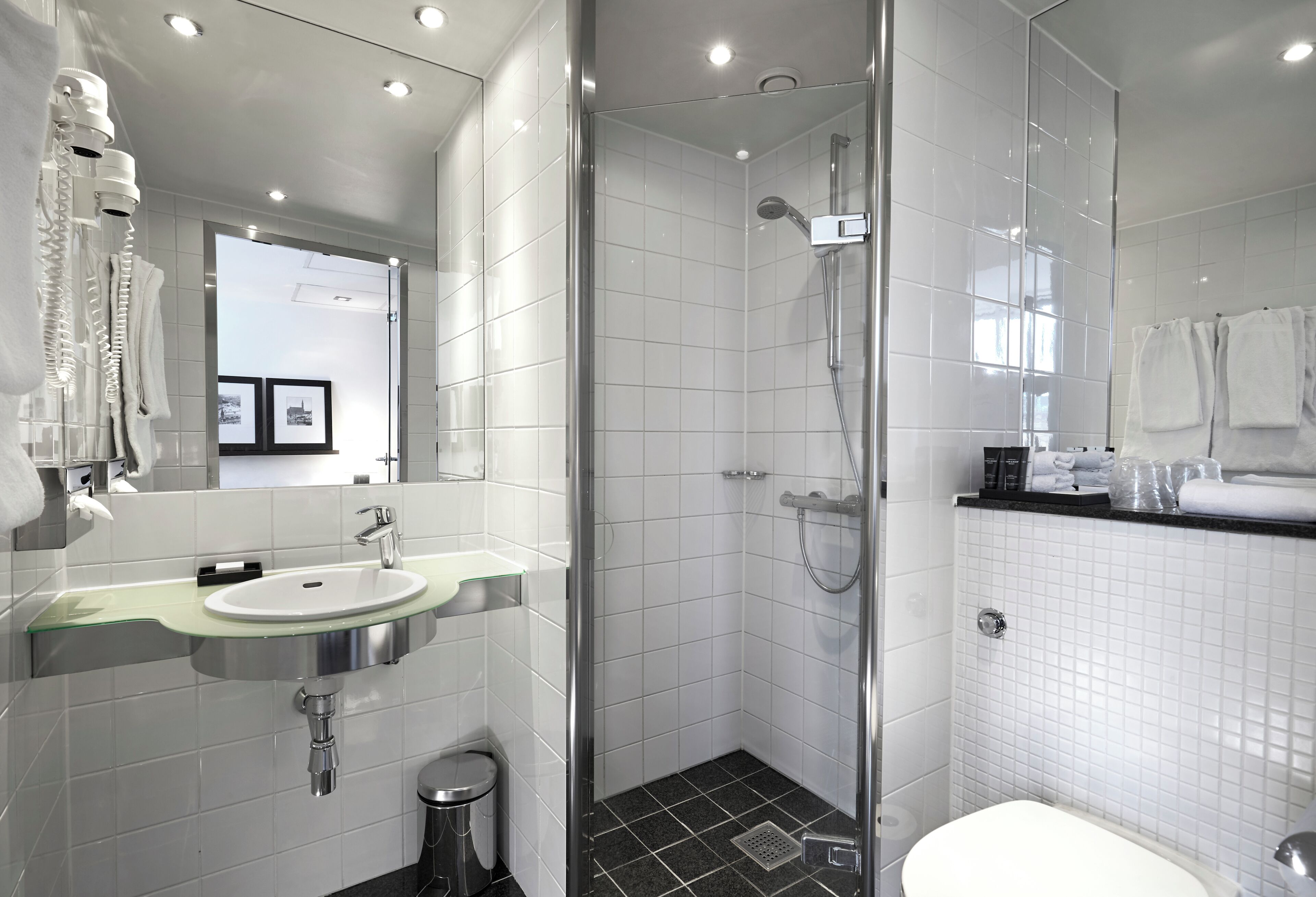 Ein modernes Badezimmer mit Duschkabine aus Glas, einem Waschbecken mit Glasbecken und einer Toilette.
