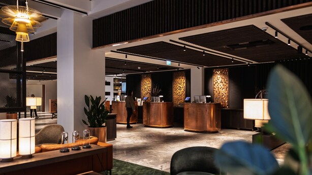 A modern lobby with a reception desk, seating area, and decorative plants. - The Square (Copenhagen)