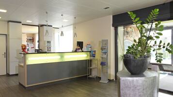 A reception area with a counter, a plant, and a window.