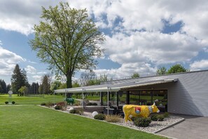 Enjoy a meal in our outdoor dining area surrounded by a serene lawn and a beautiful tree.