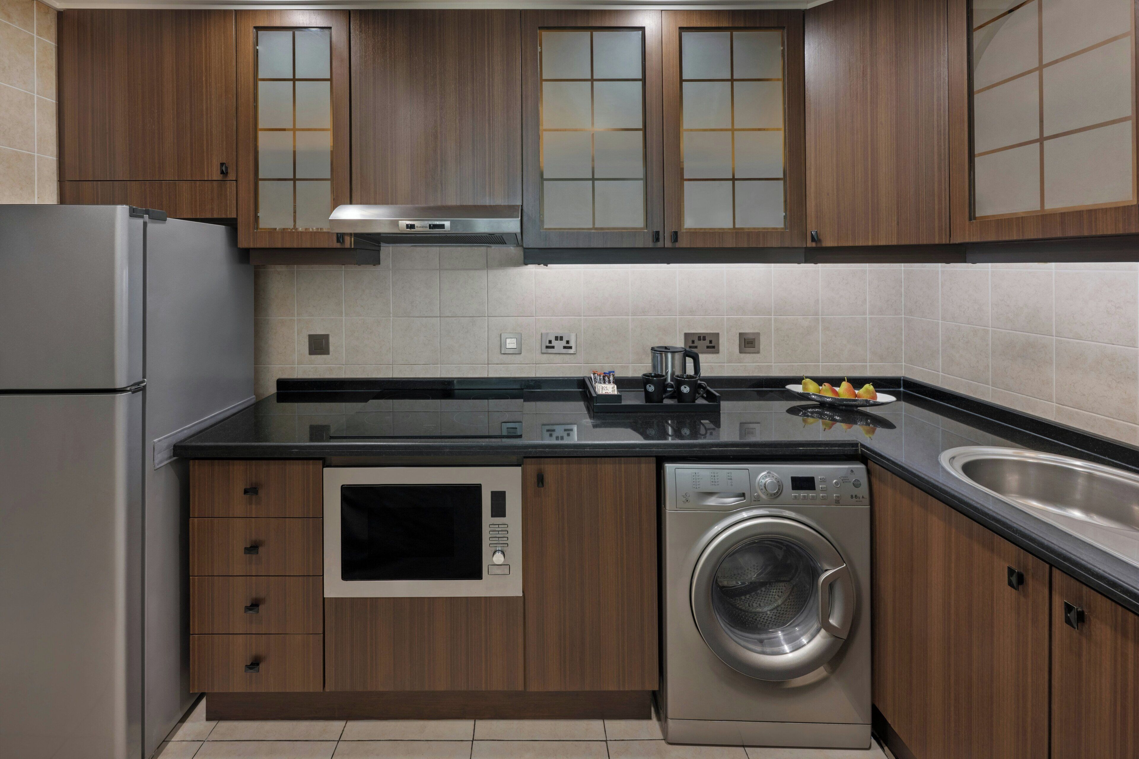 Una cocina moderna con armarios de madera, un refrigerador de acero inoxidable, horno empotrado, lavavajillas y pileta.