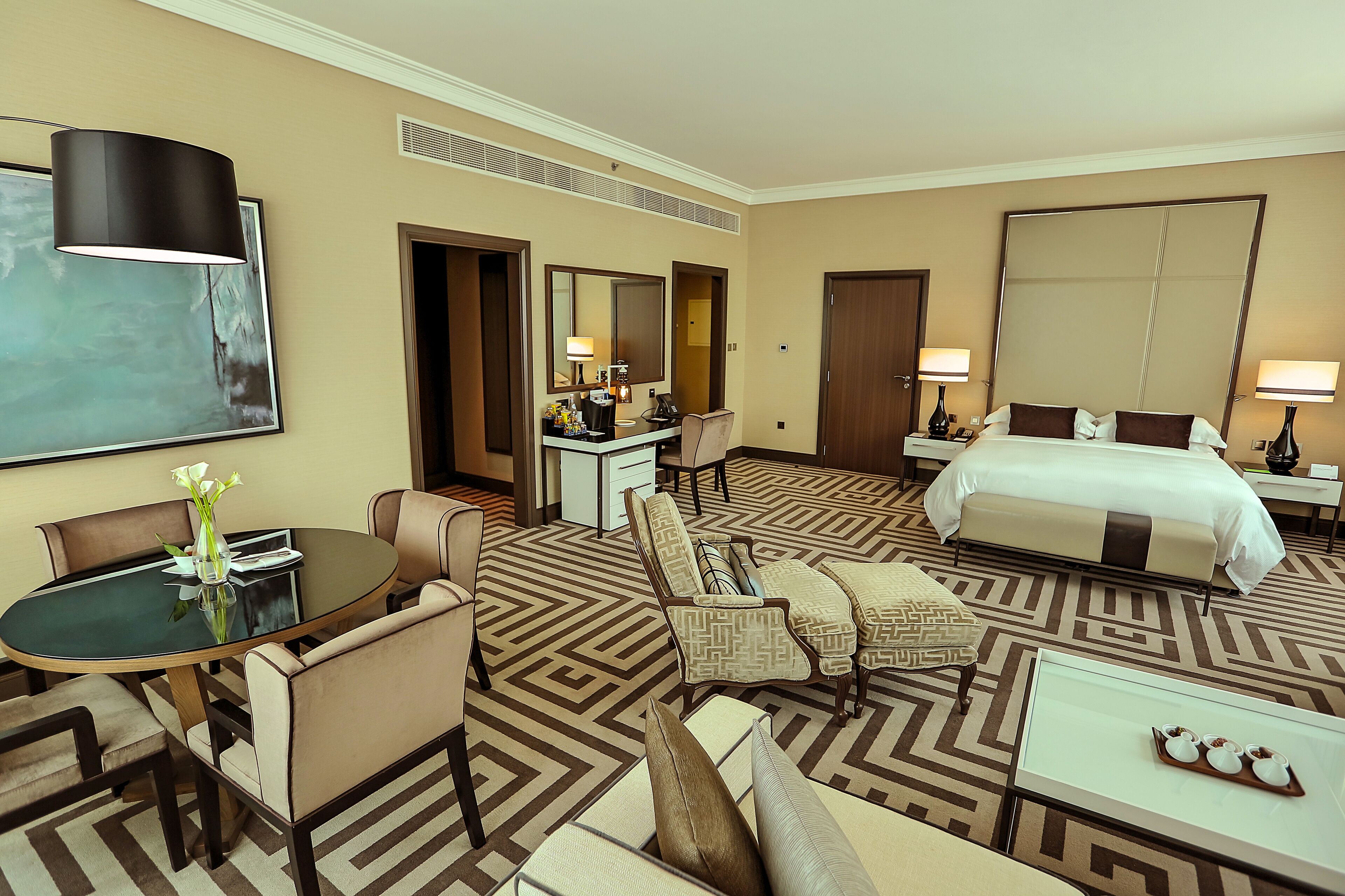 Une chambre d’hôtel comprenant un lit, un bureau, une chaise, un canapé, une table et un grand miroir.