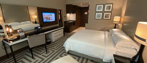 Una habitación de hotel con una cama, un escritorio con computadora, un televisor y una zona de estar.